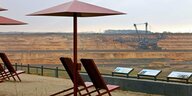 Stühle und Schirme aus Eisen auf einer Aussichtsplattform, Blick auf Tagebau