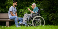 Der junger Altenpfleger unterhält sich mit einer Heimbewohnerin im Rollstuhl